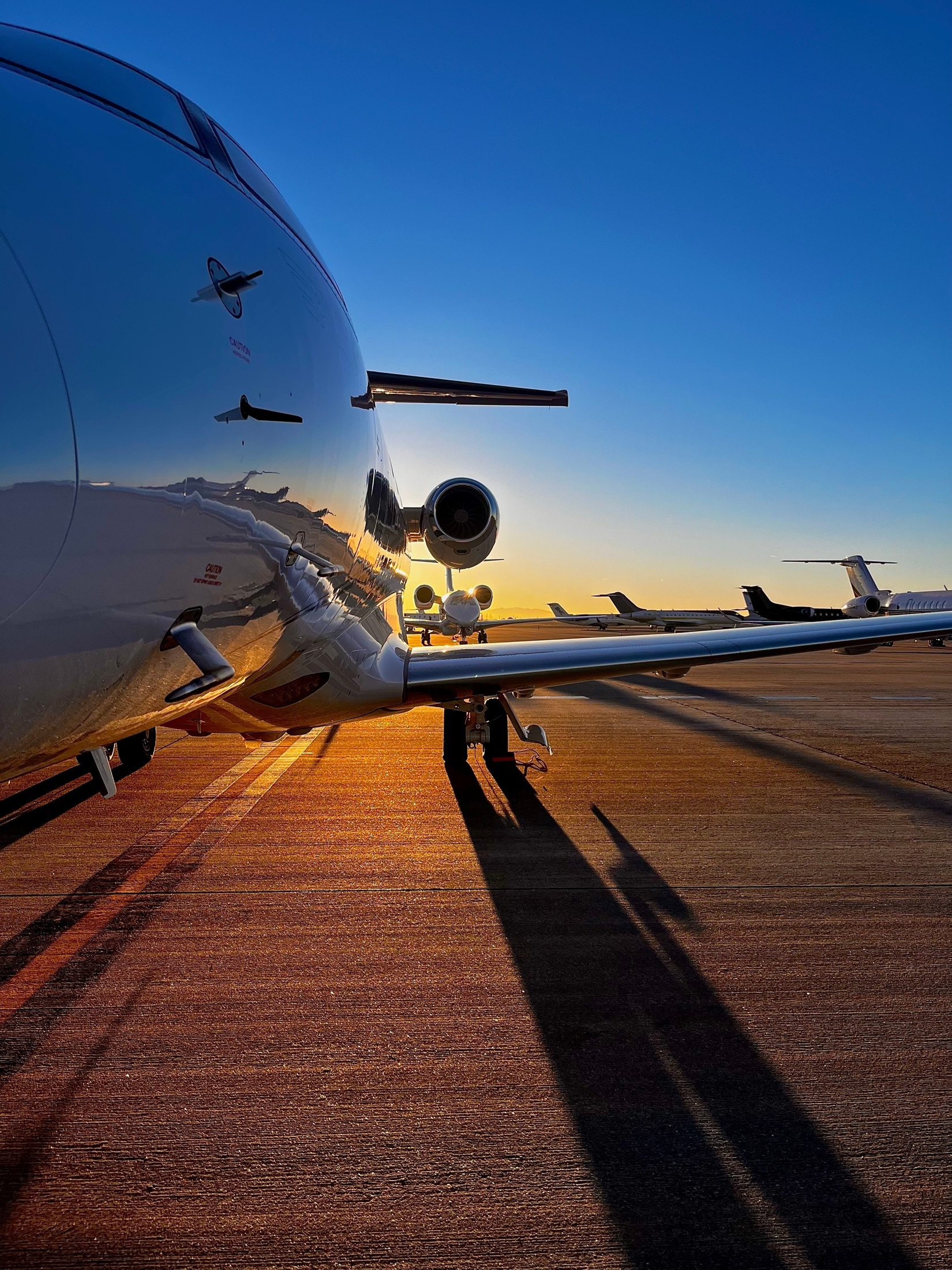 Private jets parked on a runway at sunset representing globally mobile wealth