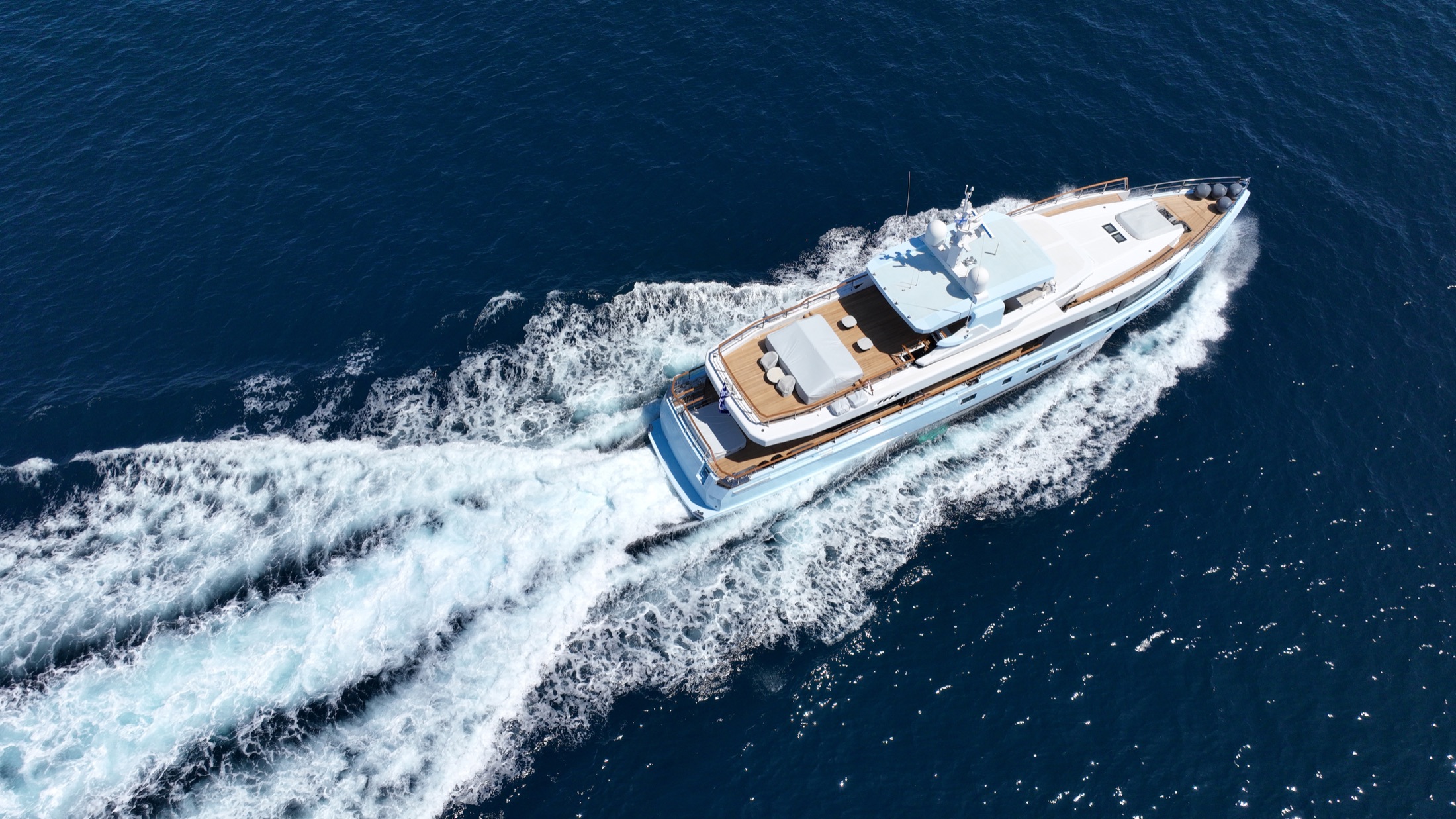 Aerial view of a yacht crossing deep blue water as a symbol of portable quiet capital