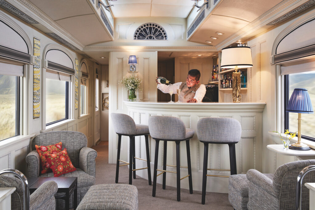 Bartender pouring a glass  of champagne at the bar in The Andean Explorer train.