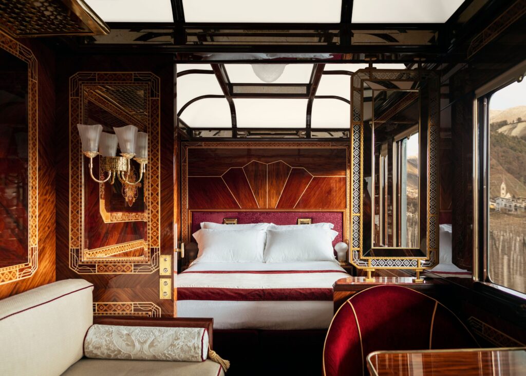 Bedroom with luxury wood walls and red velvet accents in the Venice Simplon-Orient-Express train.