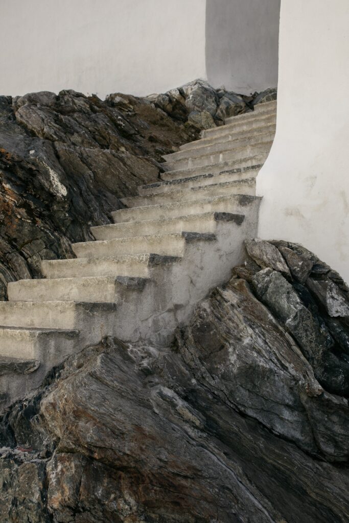Stone stairs surrounded by white walls and dark grey rock formations. 